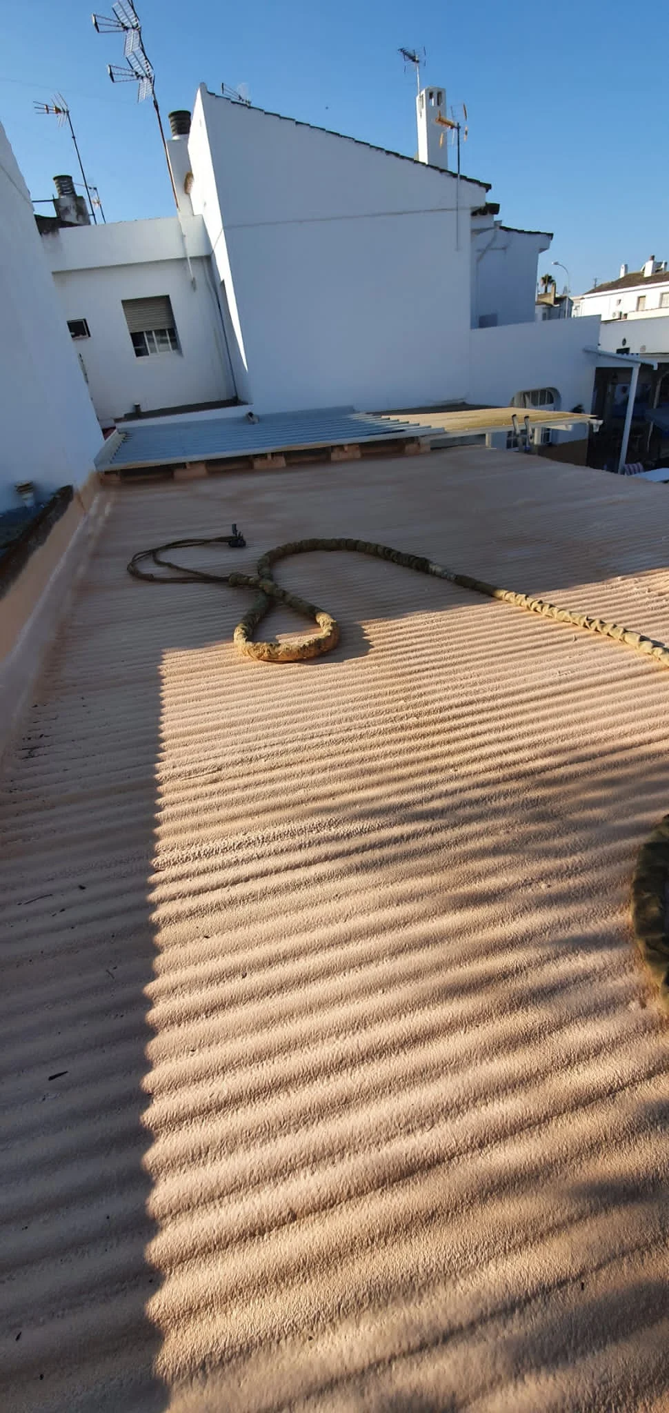 Cubierta de fibrocemento de una vivienda entre medianeras aislada con poliuretano proyectado