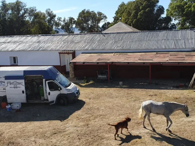Furgoneta y equipo de proyectado junto a una nave ganadera antes de aislar la cubierta