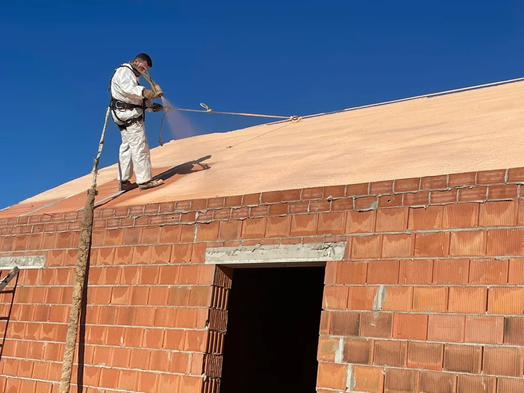 Aplicador con arnés de seguridad proyectando poliuretano en la cubierta de una nave