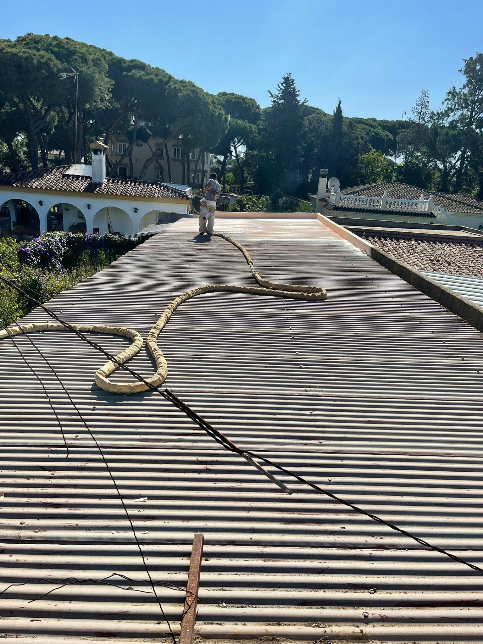 Aplicador proyectando poliuretano sobre la cubierta de chapa de un chalet