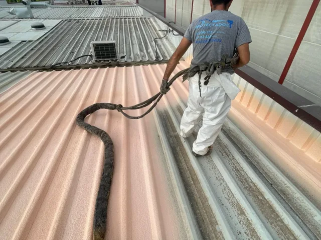 Aplicador proyectando poliuretano sobre la cubierta de una nave industrial