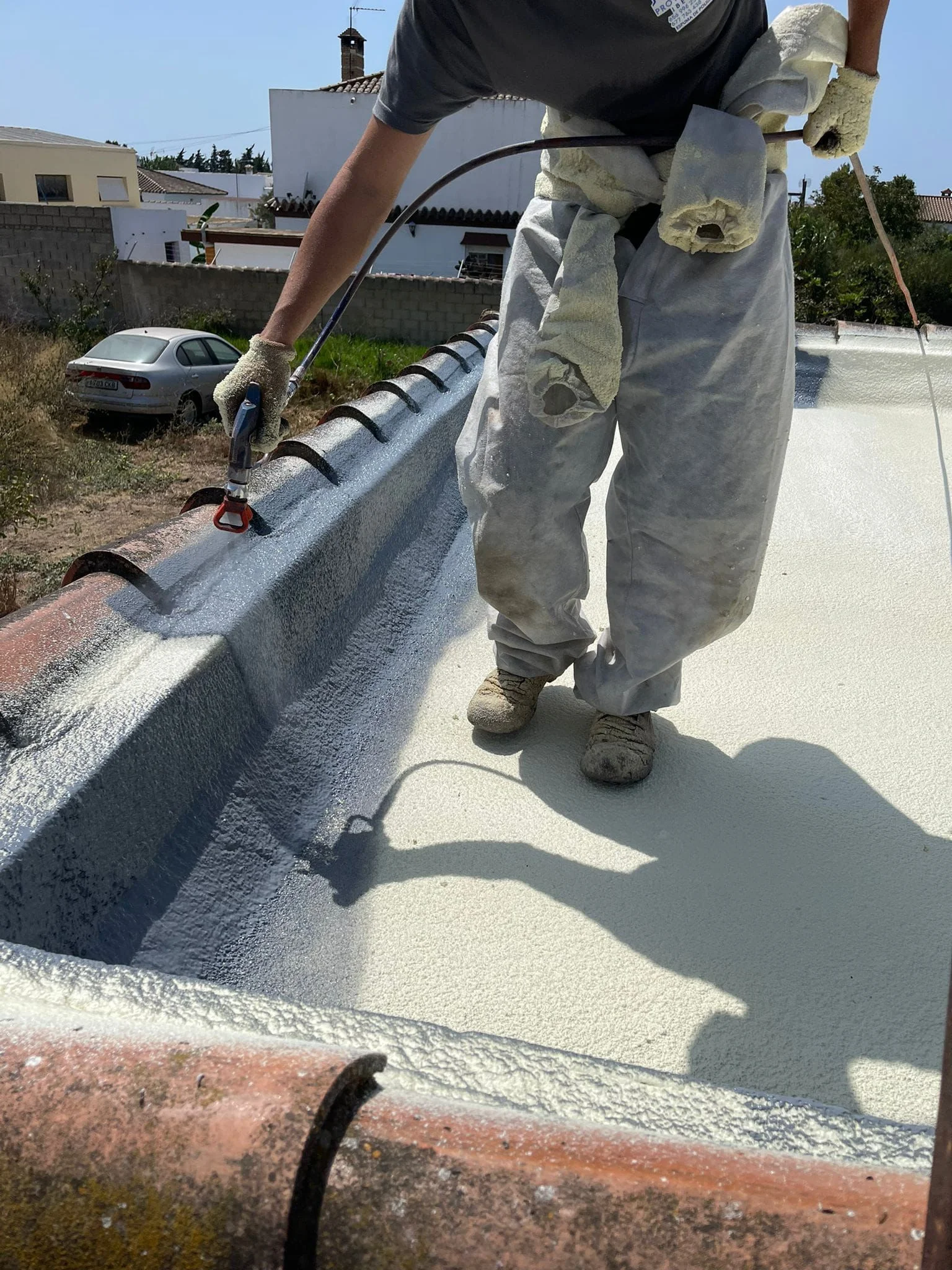 Operario rematando el canalón de una cubierta con el acabado blanco impermeabilizante